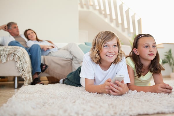 Siblings lying on the carpet watching tv together