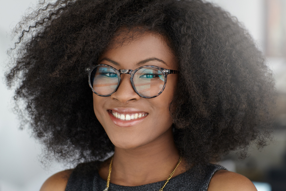 Portrait of a smiling business woman with an afro in bright glass office